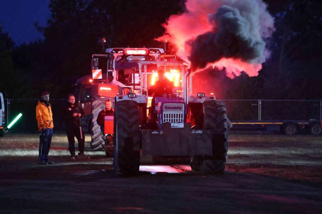 Nightpulling: Trecker im Scheinwerferlicht unter rot leuchtender Rauchwolke