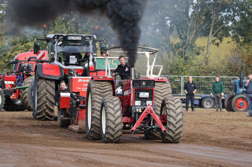 Roter Trecker mit hoher schwarzer Rauchfahne vor dem Fahrerlager